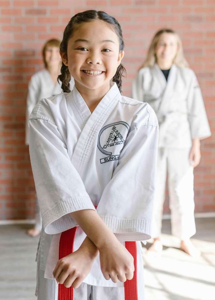 girl in gi smiling in front of other girls